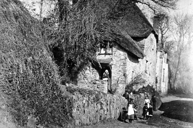 Image from the Hubert Snowdon slide collection of Thurlestone, Burnt cottage with a lady in doorway, group of people by the wall. Thatchways in background.