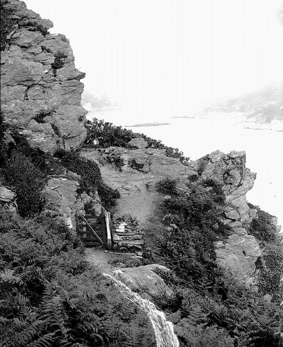 'Pathway to Bolt Head'. Looking back up the estuary, with the Blackstone etc. dimly seen in background. 
Gate in foreground. Yellow paint on plate forms waterfall-shaped mark in foreground.