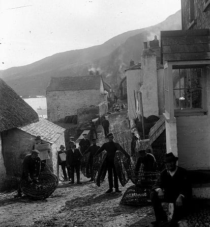 Fishermen carrying crab pots along the street at Hallsands. 'Prettyjohn' house on right.