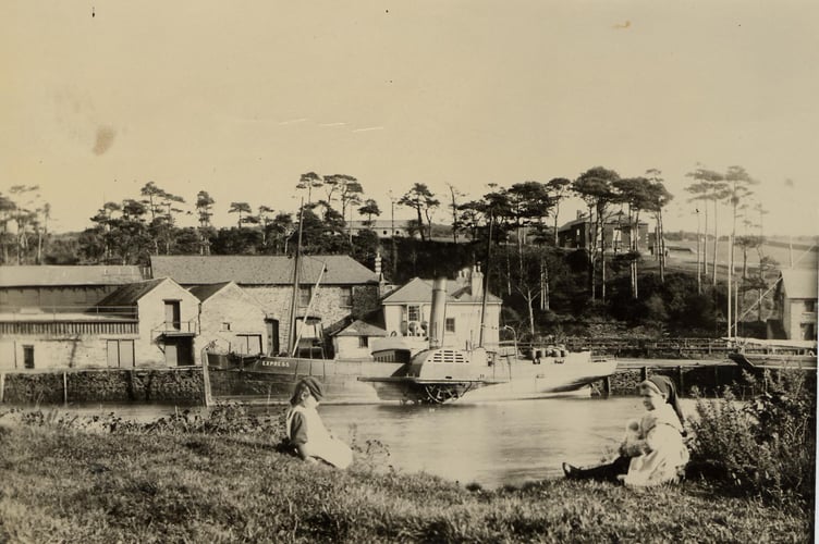 Around 1900 Bonds Quay, Kingsbridge, from west bank of estuary, with paddle steamer 'Express' berthed in background. Two children in foreground.  Napoleonic war barracks in right background.